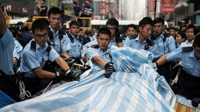 Полиция расчищает укрытие в лагере протеста за демократию в районе Монгкок в Гонконге 26 ноября 2014 года. Власти Гонконга продолжают очистку от основного места проведения акции протеста за демократию, на следующее утро после того, как произошла драка в полиции Использовали перцовый баллончик и арестовали 116 человек.