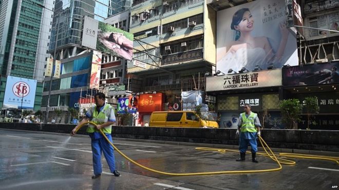 Рабочие разбрызгивают дорогу, ранее занятую сторонниками движения за демократию, после того, как 26 ноября 2014 года полиция завершила расчистку места массового протеста в районе Монгкок в Гонконге.
