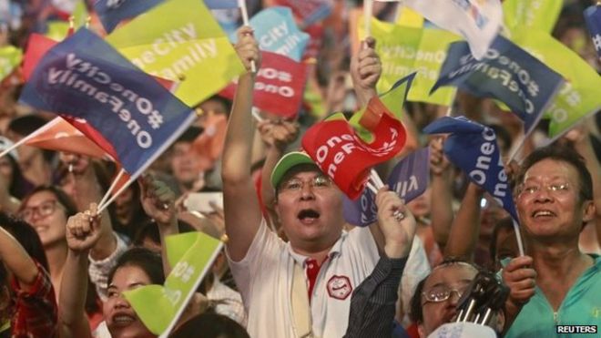Сторонники развевают флаги после того, как кандидат в мэры Тайбэя Ко Вэнь-цзе выиграл местные выборы в Тайване