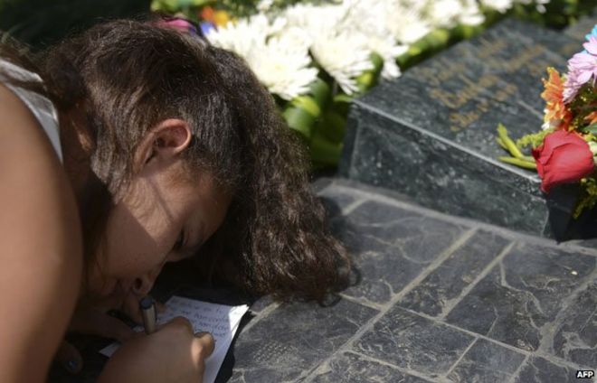 Девушка пишет записку на могиле Пабло Эскобара