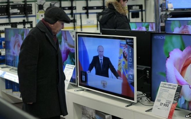 Покупатель наблюдает за президентом Путиным в телевизионном магазине в Москве (4 декабря)