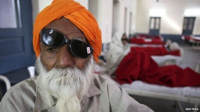 A man sits on a bed while waiting for treatment at a hospital after undergoing cataract removals from a free eye surgery camp, in the northern Indian city of Amritsar December 5