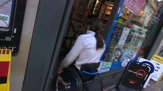 Мужчина в инвалидной коляске входит в магазин