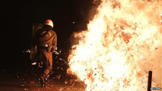 Сотрудники ОМОНа уклоняются от бензиновой бомбы во время столкновений в центре Афин, 6 декабря 2014 года