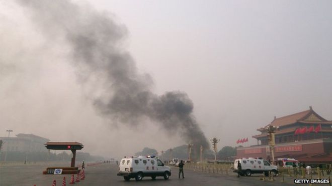 Полицейские машины перекрывают дороги, ведущие к площади Тяньаньмэнь, так как дым поднимается в воздух после того, как 28 октября 2013 года в Пекине перед Воротами Тяньаньмэнь врезался автомобиль