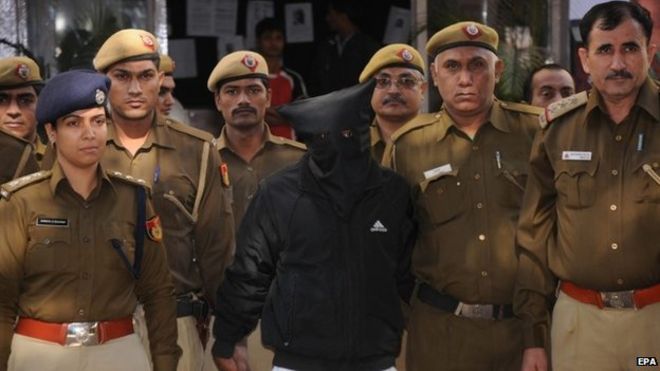 Сотрудники полиции сопровождают водителя такси (в маске), обвиняемого в изнасиловании женщины-руководителя финансовой компании, когда его доставляют в суд в Нью-Дели, 8 декабря 2014 года.