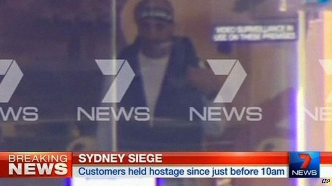 На этом снимке, снятом с видео, изображен мужчина, считающийся вооруженным человеком, Ман Харон Монис, в кафе в Сиднее, Австралия, понедельник, 15 декабря 2014 года.