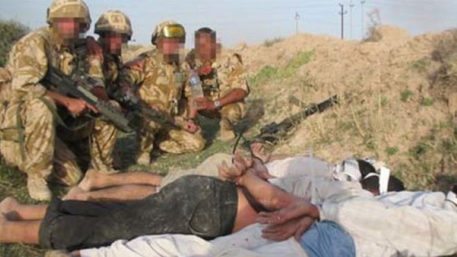 Британские солдаты с иракскими заключенными, которые связаны и лежат на земле лицом вниз