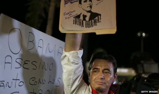 Мужчина держит знак президента Барака Обамы в Майами, штат Флорида, 17 декабря 2014 года