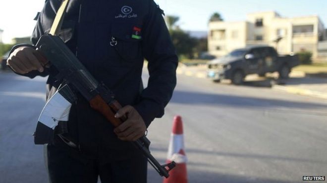 Офицер безопасности стоит с оружием на дороге, ведущей в полицейский участок в Бенгази - 4 декабря 2014 года