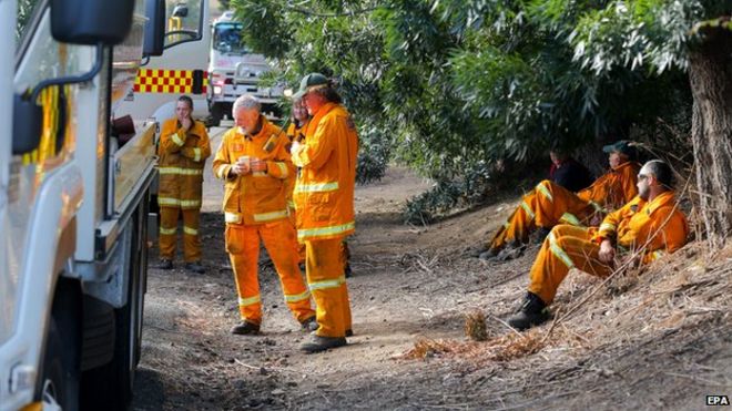 Пожарные из пожарной охраны добровольцев страны отдыхают после тушения лесных пожаров на холмах Аделаиды в Гумераче, Австралия, 4 января 2015 г.