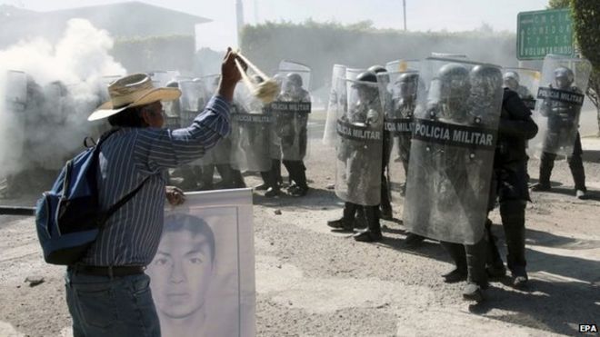 Родственники 43 пропавших мексиканских студентов сталкиваются с полицией, когда они пытаются войти в военные объекты в Игуале 12 января 2014 года