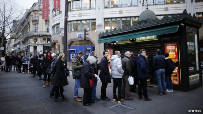 Люди стоят в очереди, чтобы получить копию сатирического французского журнала Charlie Hebdo перед киоском в Париже 14 января 2015 года.
