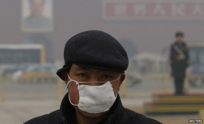 Мужчина в маске во время грязного дня на площади Тяньаньмэнь в Пекине