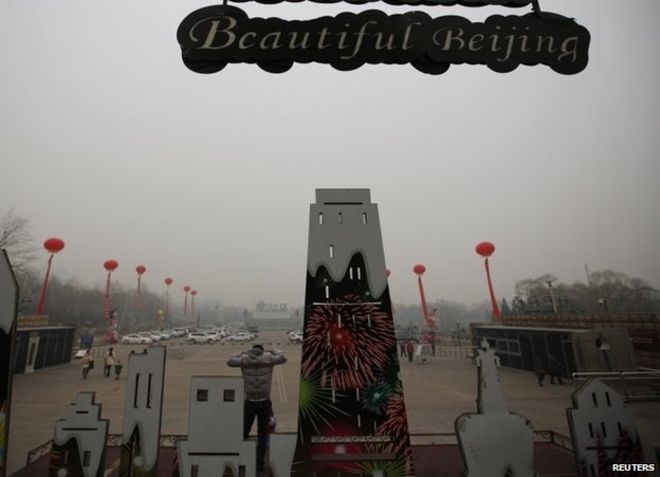 Мужчина стоит на платформе, позируя для картины у башни обсерватории в грязный день в Пекине