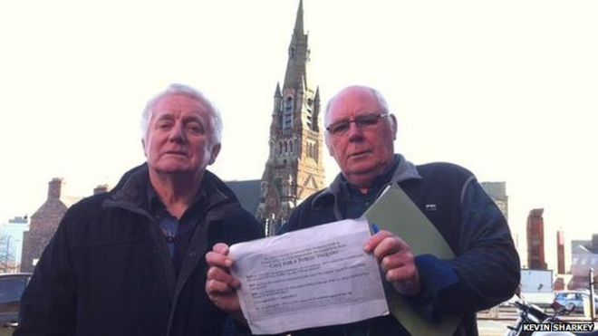 Мужчины держат знак протеста в Белфасте