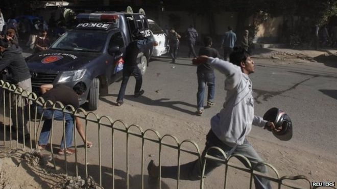 Протестующий бросает камни в полицейских во время акции протеста в Карачи 16 января