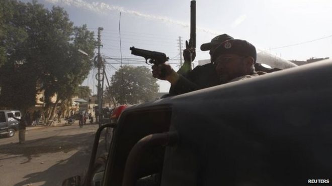 Полицейский использует свой пистолет для разгона протестующих во время акции протеста в Карачи 16 января