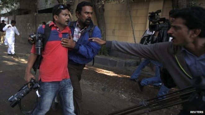 Асифу Хасану (слева), застреленному во время акции протеста против сатирического французского еженедельника Charlie Hebdo, помогает другой фотограф в Карачи 16 января