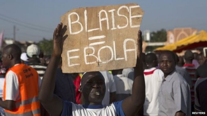 Протестующий держит в руках знак, который ссылается на президента Блеза Компаоре во время демонстрации в Уагадугу, Буркина-Фасо (октябрь 2014 года)