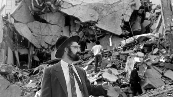 Мужчина проходит по обломкам, оставленным после взрыва бомбы в Аргентинской израильской взаимной ассоциации (Амиа) в Буэнос-Айресе 18 июля 1994 года,