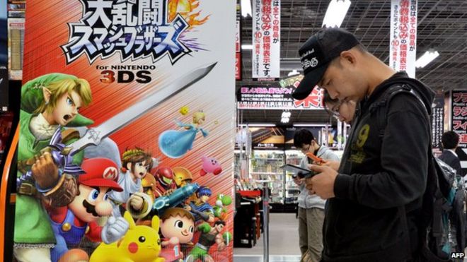 Клиенты играют в видеоигры в электрическом магазине в Токио.