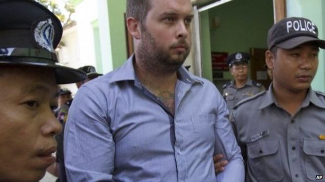 Филип Блэквуд, в центре, новозеландский генеральный директор V Gastro Bar, сопровождается сотрудниками полиции Мьянмы для судебного разбирательства в городском суде 26 декабря 2014 года в Янгоне, Мьянма.