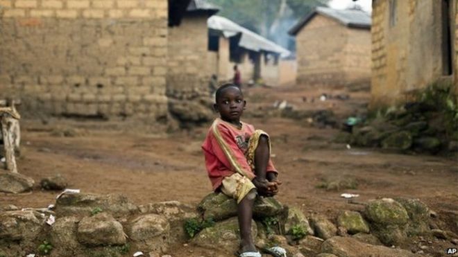 ребенок сидит в гвинейской деревне Мелианду
