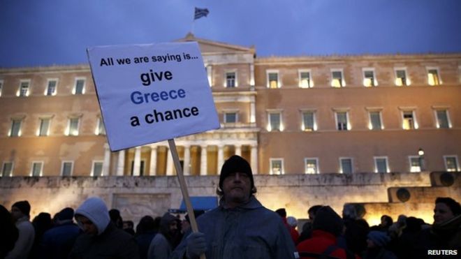 Протестующий демонстрирует знак во время проправительственной демонстрации против жесткой экономии у здания парламента Греции в Афинах 11 февраля 2015 года.