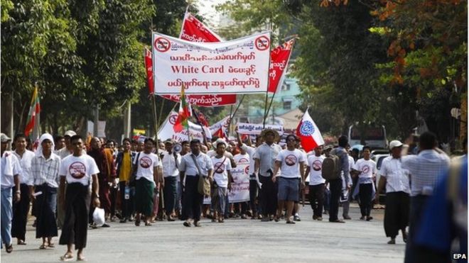 Протестующие держат плакаты и флаги, проходя мимо пагоды Шведагон во время марша протеста против решения парламента Мьянмы по вопросу Белой карты, в Янгоне, Мьянма, 11 февраля 2015 года