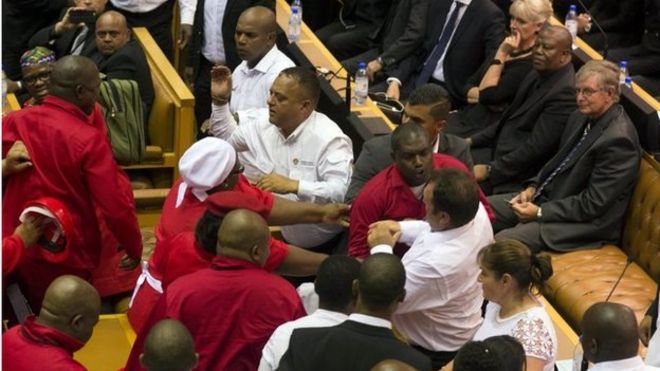 Члены организации «Борцы за экономическую свободу» (EFF) Джулиуса Малемы (в красном) сталкиваются с сотрудниками службы безопасности после того, как им было приказано выйти из зала во время выступления президента Джейкоба Зумы в Государстве Нация в Кейптауне 12 февраля 2015 года