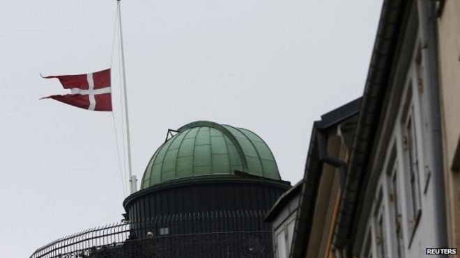 Датский флаг на мачте рядом с мемориальным местом для жертв смертельных обстрелов в Копенгагене 16.02.2015