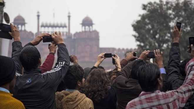 Индейцы держат в руках свой мобильный телефон, когда парад Дня Республики проходит мимо исторического Красного форта в Дели 26 января 2015 года.