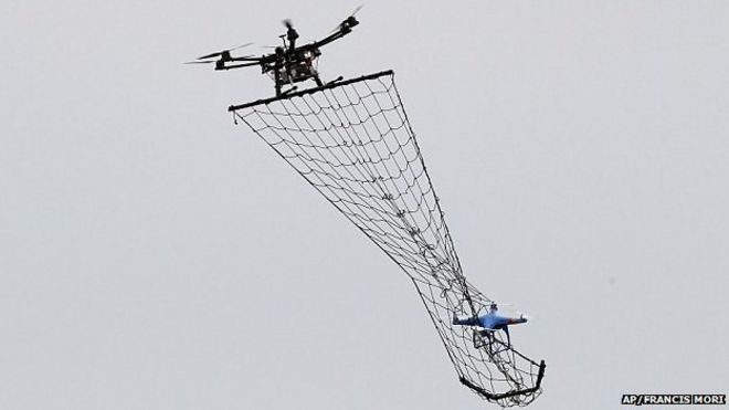 Дрон Interceptor MP200, вверху, готовится поймать беспилотник DJI Phantom 2 с сеткой во время демонстрационного полета в Ла-Куэ-ан-Бри