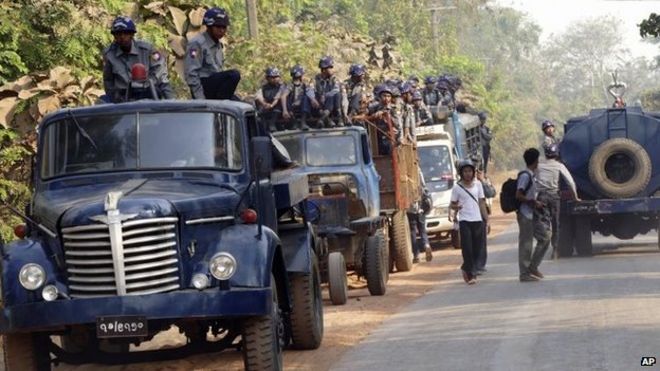 Полицейские стоят рядом, и 2 марта 2015 года возле монастыря Аунг Мие Бекман, где студенты-протестующие проводят лагерь в Летпадане, к северу от Янгона, Мьянма, ждет машина с водяной пушкой.