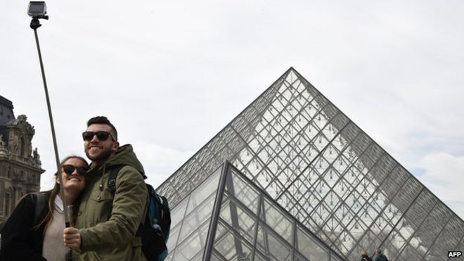 Туристы используют селфи-палку за пределами Лувра