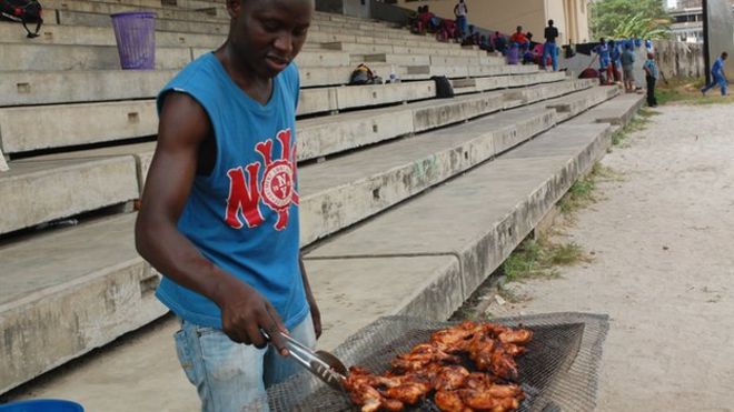 Мужчина готовит мясо для игры в крикет в Лагосе, Нигерия