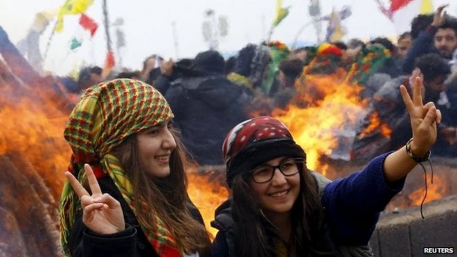 Курдские девушки жестом перед костром во время празднования праздника Новруз, который отмечает приход весны и нового года, в Диярбакыре, 21 марта 2015 года