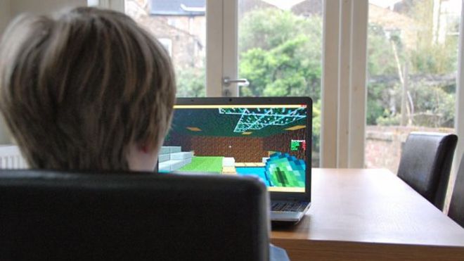 Мальчик играет в Minecraft за кухонным столом