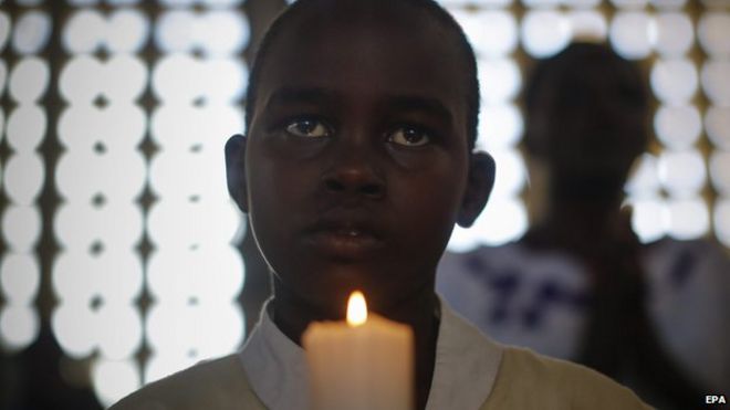 Кенийский мальчик держит свечу, вознося молитвы за 148 человек, погибших во время нападения на Университетский колледж Гариссы 5 апреля 2015 года