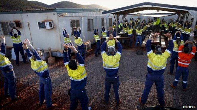 Рабочие на железорудном руднике Fortescue Solomon выполняют упражнения на растяжку в Долине Царей, примерно в 400 км (248 милях) к югу от Порт-Хедленда в регионе Пилбара, Западная Австралия, в этом фото от 2 декабря 2013 г.