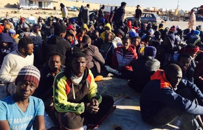 Мигранты сидят на земле в Мисрате