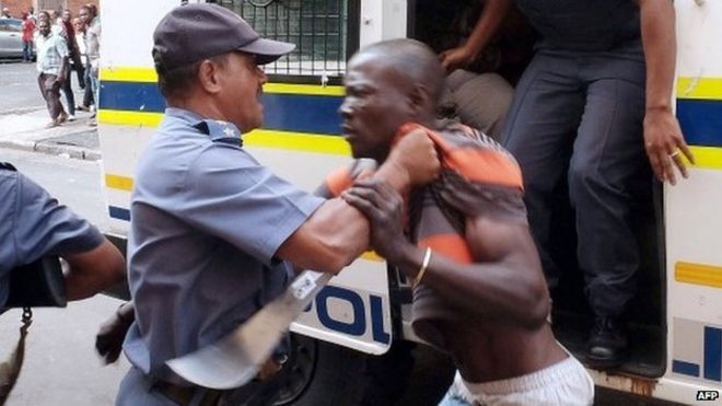 Члены Южноафриканской полицейской службы (САПС) пытаются контролировать протестующего после того, как 14 апреля 2015 года в Дурбане произошли столкновения между группой местных жителей и полицией