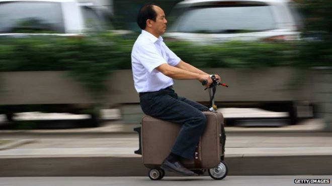 На этом снимке, сделанном 28 мая 2014 года, изображен китайский фермер Хэ Лянцай, ехавший на чемодане с моторизованным скутером, который он разрабатывал последние десять лет. Он может развивать скорость до 12,5 миль в час