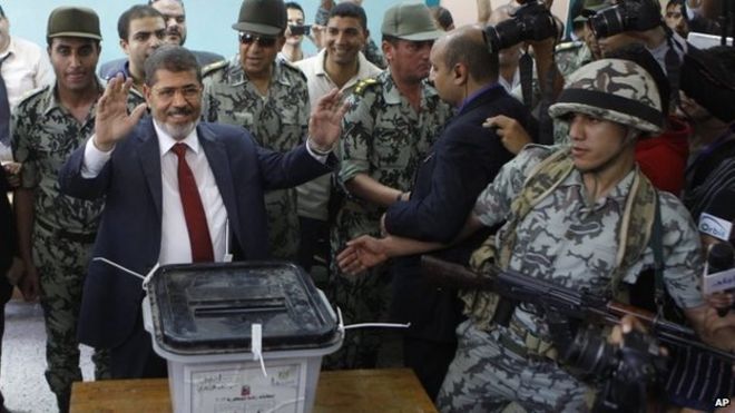 Мухаммед Мурси машет рукой после того, как он проголосовал на президентских выборах в Египте в Загазиге (16 июня 2012 года)