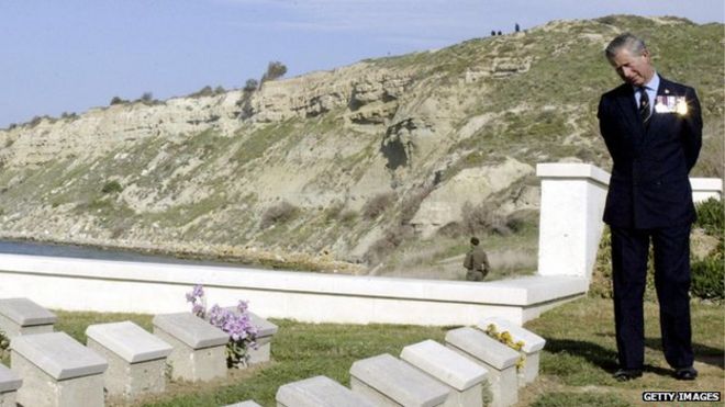 Принц Чарльз читает имена на могилах на Британском кладбище W Beach в Галлиполи, а на заднем плане - скалы и пляж, где британские солдаты погибли 90 лет назад на полуострове Галлиполи 25 апреля 2005 г.