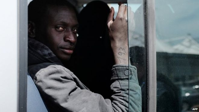 Спасенный мигрант с номером на правой руке садится в автобус после высадки с итальянского судна Guardia di Finanza Denaro в сицилийской гавани Катании 23 апреля 2015 года
