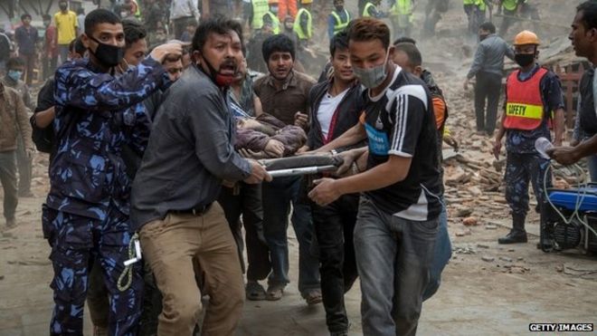 Аварийно-спасательные службы несут жертву землетрясения на носилках после обрушения башни Дхарара в Катманду (25 апреля 2015 г.)