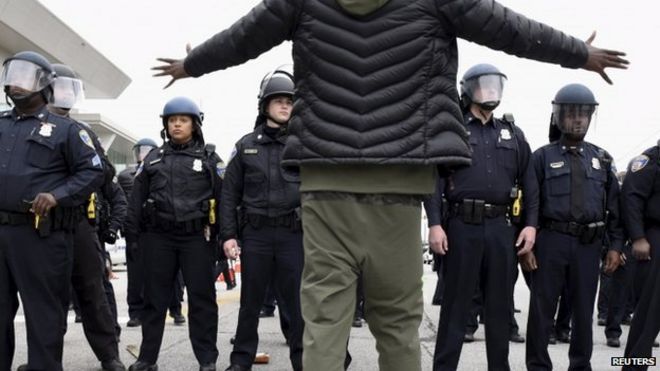 Демонстрант жестом указывает на линию полиции возле Камден Ярдс во время акции протеста против гибели Фредди Грея в Балтиморе во время содержания под стражей 25 апреля 2015 г.