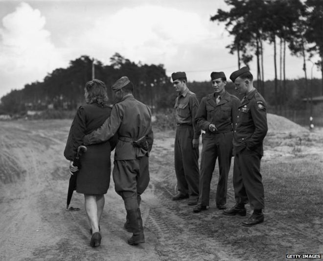 Примерно в 1945 году: солдаты смотрят, как один из их русских союзников выходит на прогулку со своей девушкой по Берлину